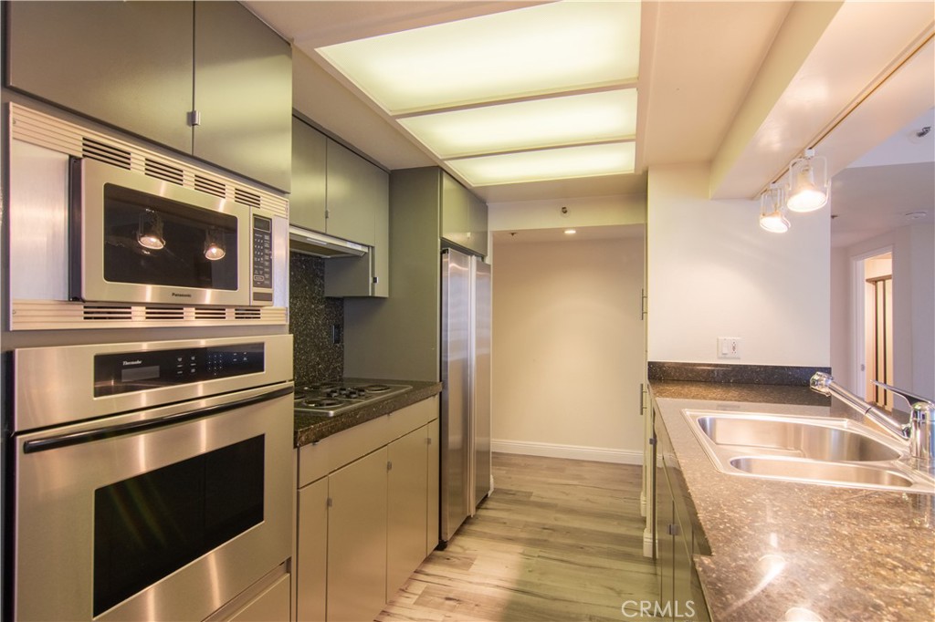 600 West 9th Street, Unit 1114 Los Angeles, CA 90015 - Photo 11 of 27 a kitchen with stainless steel appliances kitchen island granite countertop a stove and a sink
