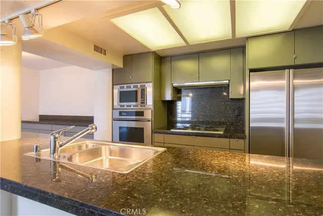 a kitchen with stainless steel appliances granite countertop a sink and a refrigerator