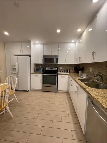 a kitchen with granite countertop a sink a counter top space stainless steel appliances and cabinets