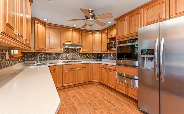 a kitchen with stainless steel appliances granite countertop a sink a stove and a refrigerator