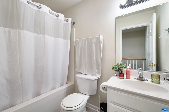 a bathroom with a sink a toilet a mirror and shower curtain