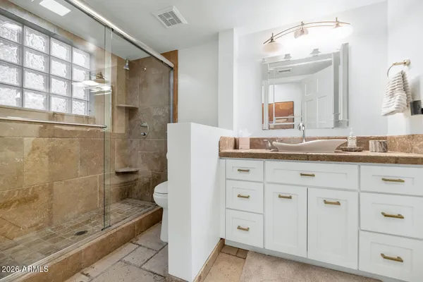 a bathroom with a granite countertop sink a mirror and a shower