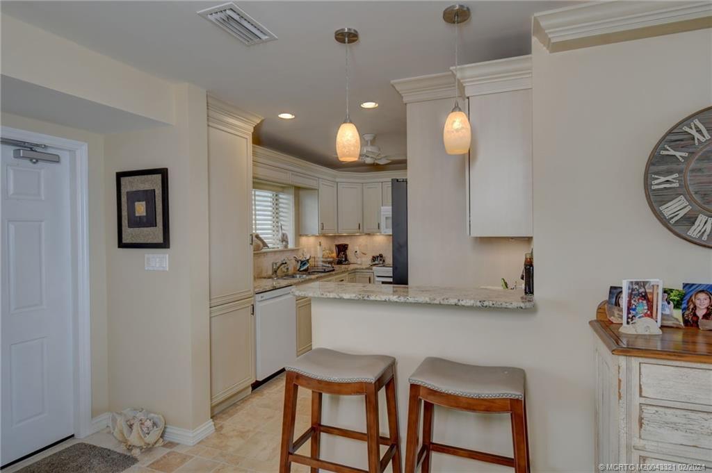 2375 Northeast Ocean Boulevard, Unit E405 Stuart, FL 34996 - Photo 18 of 58 a kitchen with granite countertop white cabinets and chairs