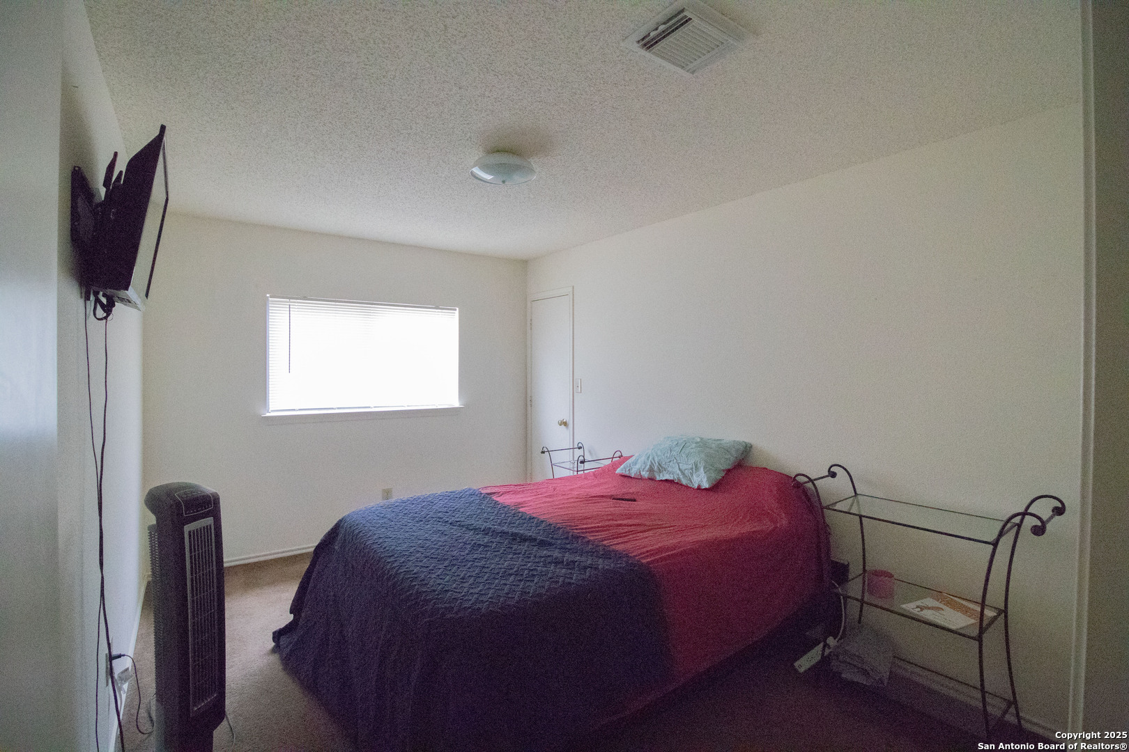 797 Killarney Road Floresville, TX 78114 - Photo 21 of 35 a bedroom with a bed and a flat tv screen on the dresser