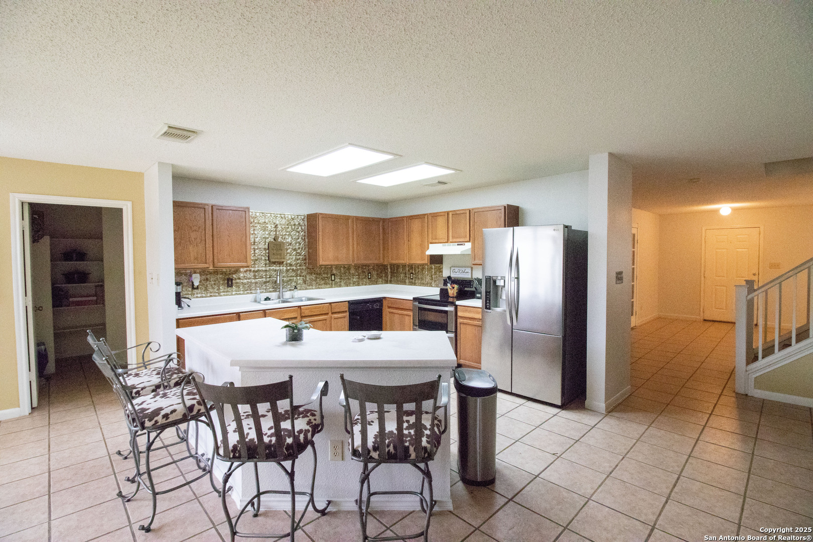 797 Killarney Road Floresville, TX 78114 - Photo 9 of 35 a kitchen with stainless steel appliances a dining table chairs and a refrigerator