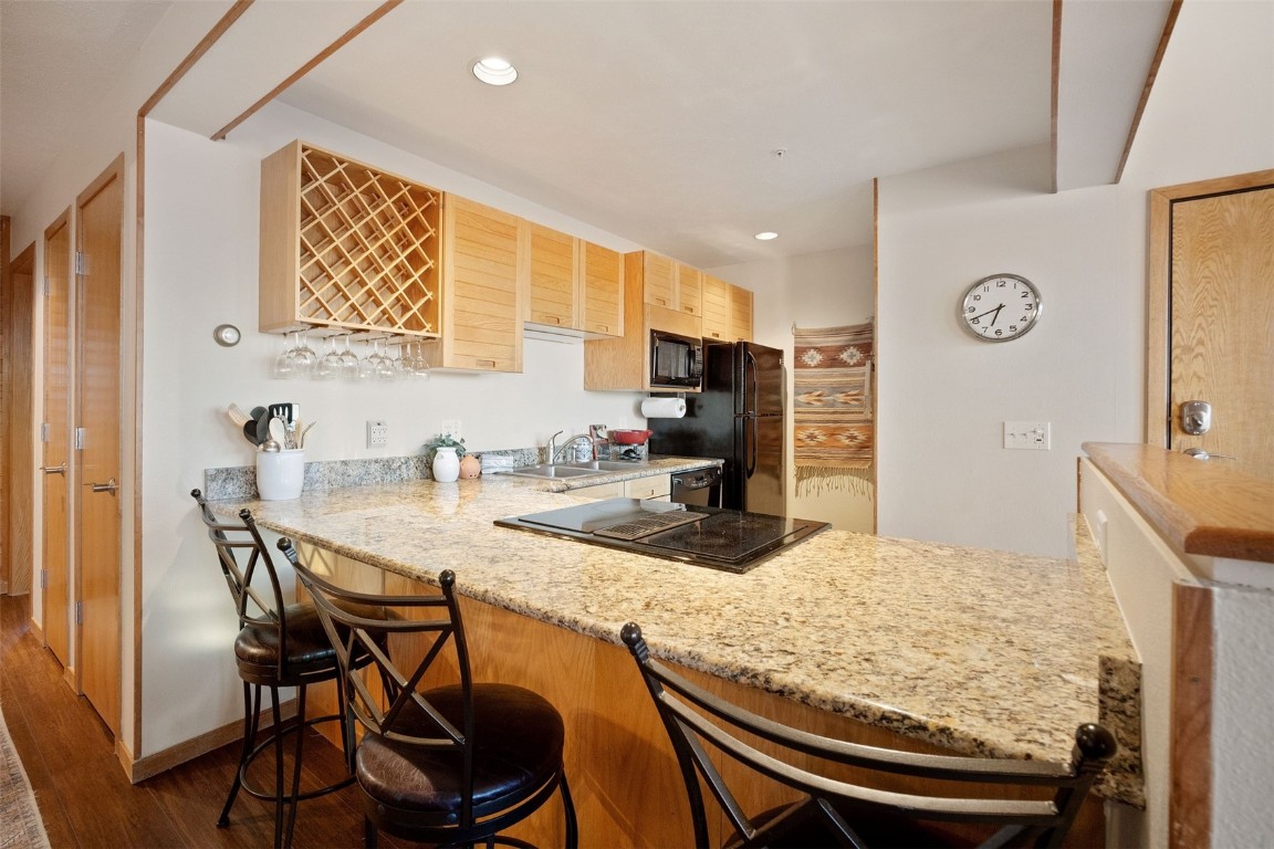 91400 Ryan Gulch Road, Unit 91425 Silverthorne, CO 80498 - Photo 10 of 42 a kitchen with granite countertop sink table and chairs