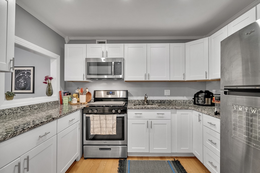 32 Juniper Street, Unit 91 Brookline, MA 02445 - Photo 8 of 21 a kitchen with granite countertop white cabinets and stainless steel appliances