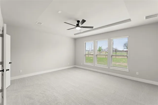 an empty room with chandelier fan and windows