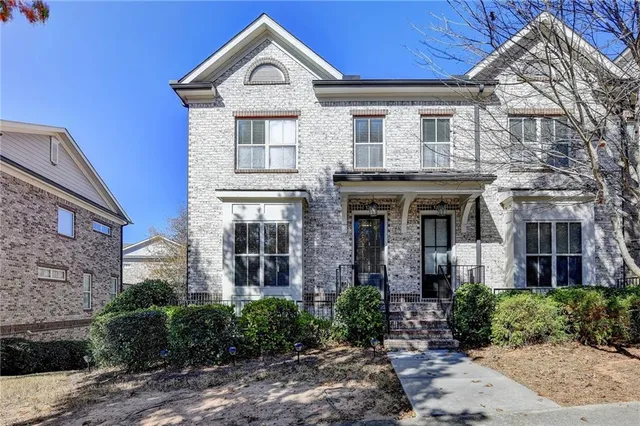 a view of a brick house with large windows and a tree