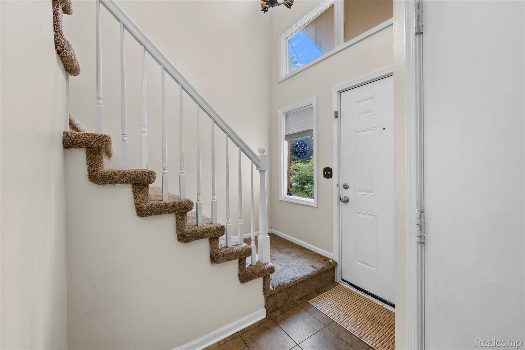 200 Fraser Street Rochester, MI 48307 - Photo 11 of 29 Two-story entryway with a tile floor, carpeted staircase with white balusters, and a transom window above the entry door