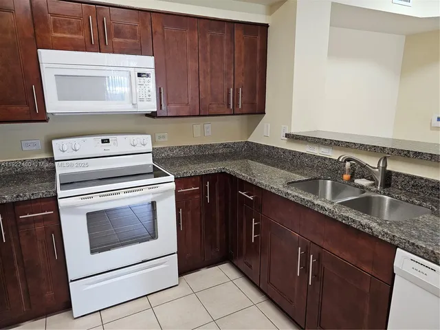 a kitchen with granite countertop a sink stove and cabinets