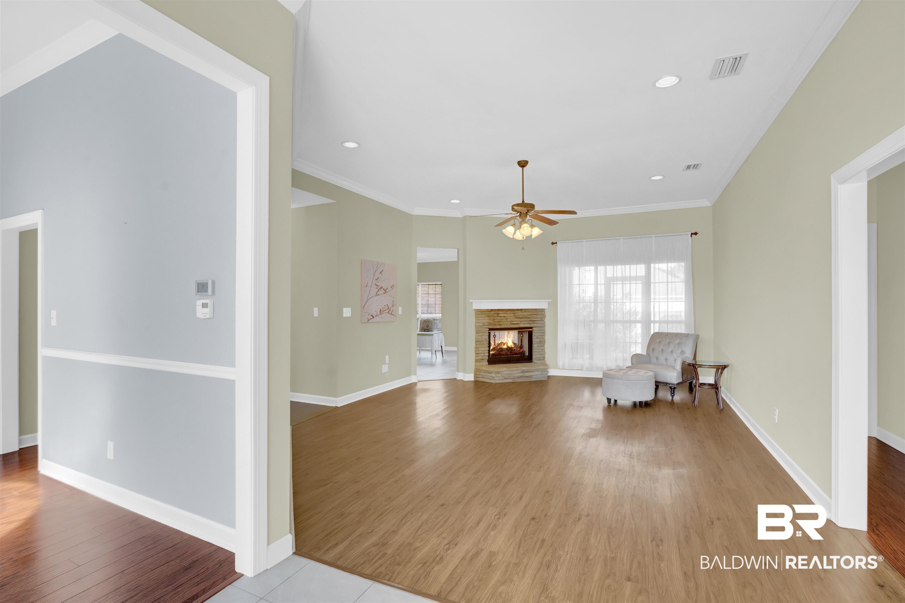 100 Conti Court Fairhope, AL 36532 - Photo 16 of 54 Unfurnished living room featuring ceiling fan, a stone fireplace, ornamental molding, and light hardwood / wood-style flooring