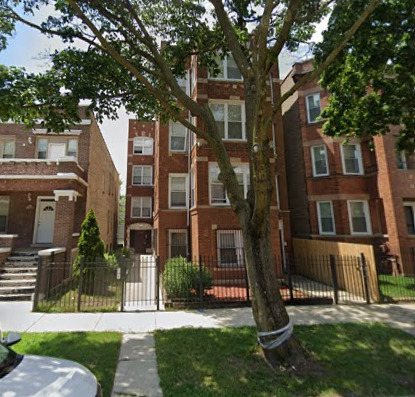 a view of a brick house next to a yard with big trees