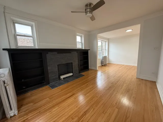 a view of a room with wooden floor fireplace and windows