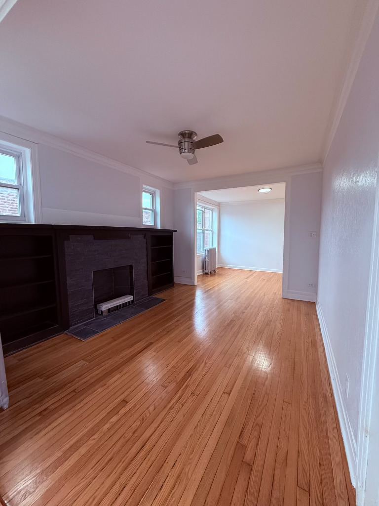 6928 South Green Street, Unit 2N Chicago, IL 60621 - Photo 3 of 11 a view of an empty room with wooden floor fireplace and a window