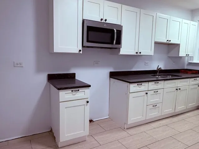 a kitchen with granite countertop white cabinets and stainless steel appliances