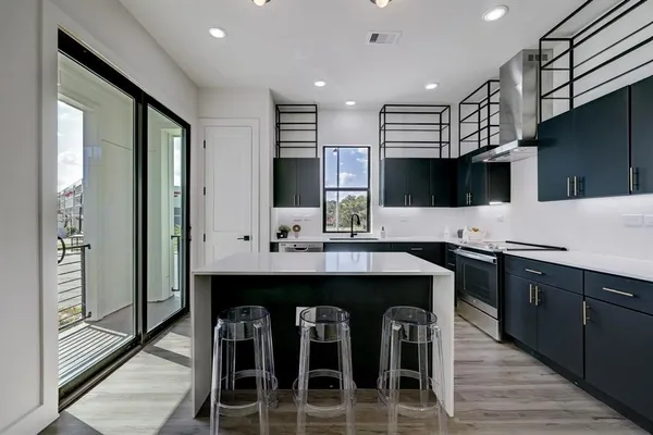a kitchen with stainless steel appliances granite countertop a table chairs sink and cabinets