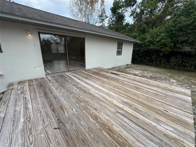 a view of backyard with a wooden deck and floor to ceiling window
