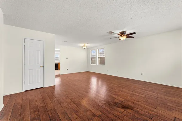a view of an empty room with a window and wooden floor