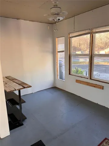 an empty room with windows and ceiling fan