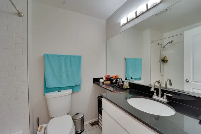 a bathroom with a granite countertop toilet sink and mirror