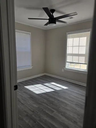 a view of empty room with wooden floor and fan