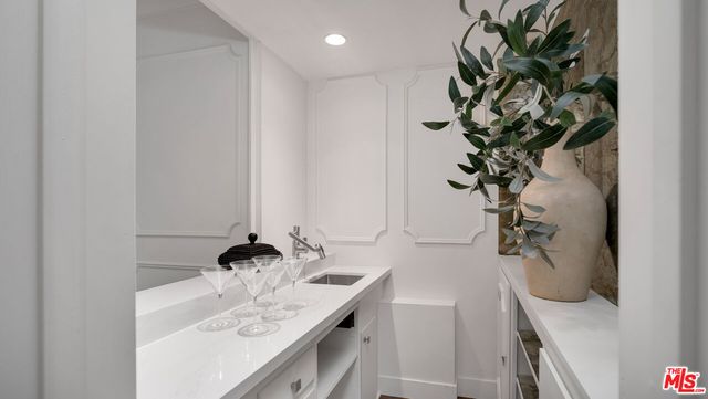 a bathroom with a sink a mirror and a potted plant