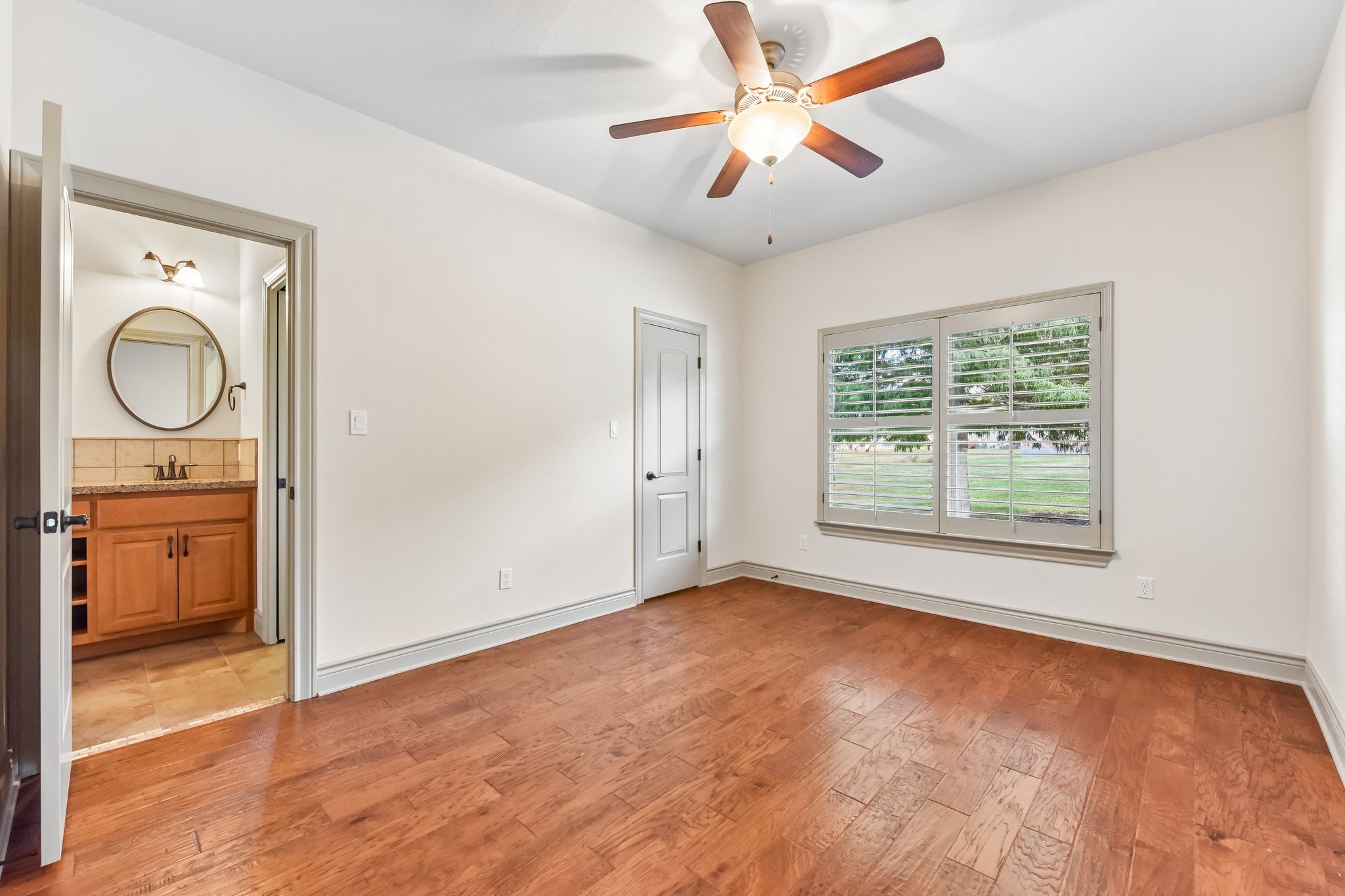163 Powder Horn Road Bastrop, TX 78602 - Photo 21 of 34 Rich hardwood flooring anchors this comfortable bedroom complete with adjacent bathroom access.