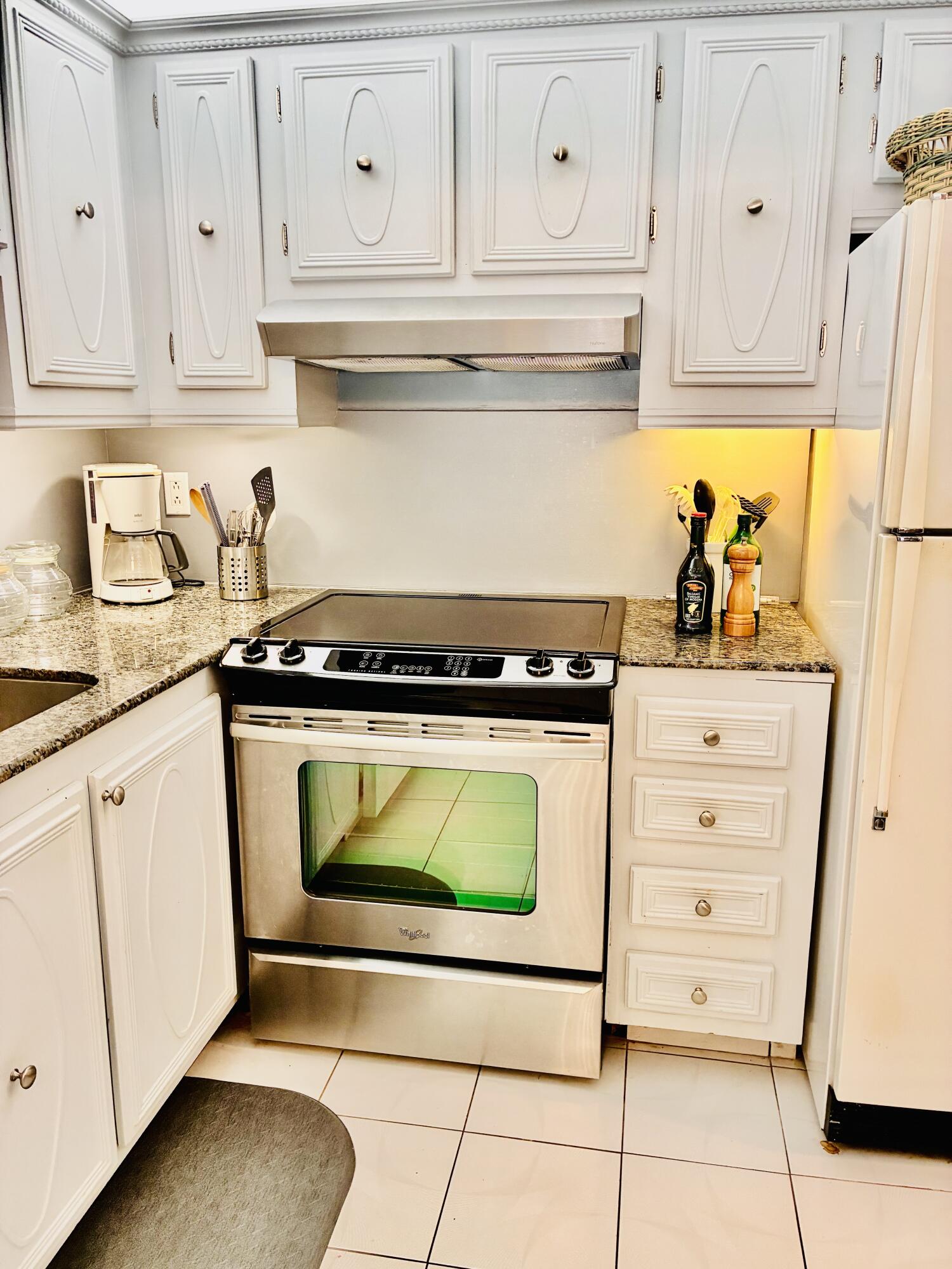259 South Cypress Road, Unit 533 Pompano Beach, FL 33060 - Photo 4 of 19 a kitchen with white cabinets and a stove with wooden floor