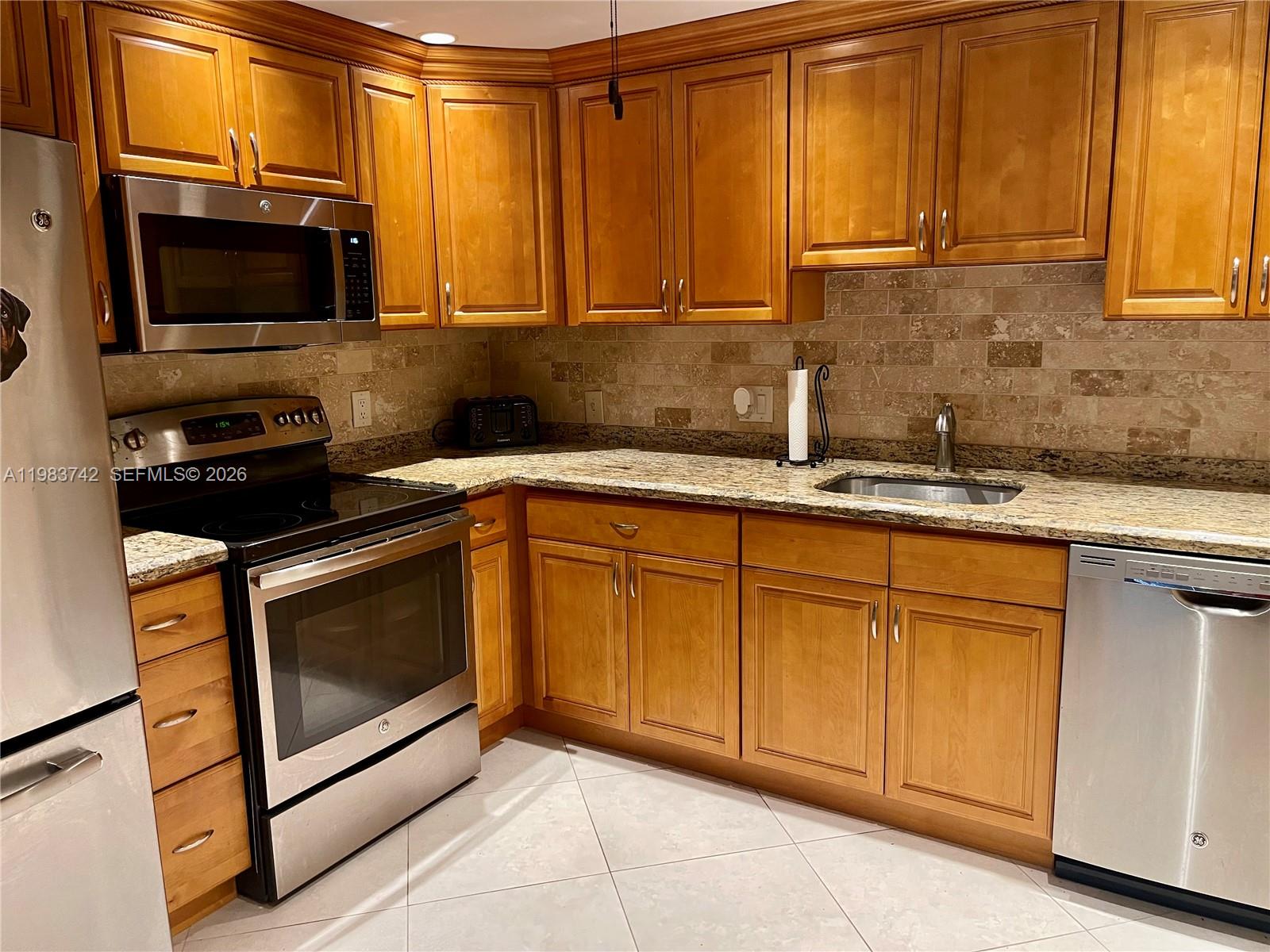 2042 Newcastle A, Unit 2042 Boca Raton, FL 33434 - Photo 3 of 17 a kitchen with stainless steel appliances granite countertop a stove microwave and sink