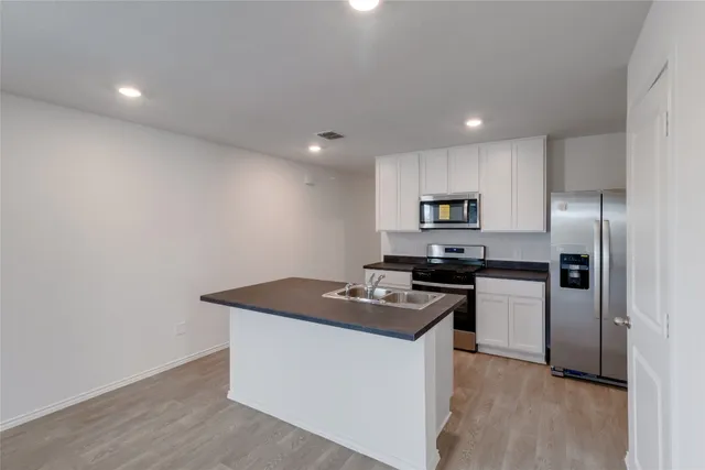 a kitchen view with stainless steel appliances granite countertop a stove a refrigerator and a sink