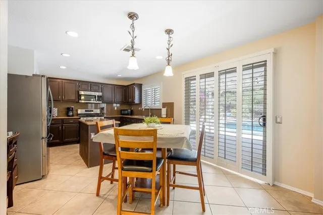 a dining room with stainless steel appliances kitchen island granite countertop a dining table and chairs