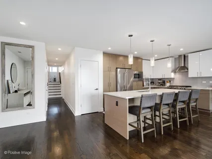 a kitchen with stainless steel appliances kitchen island granite countertop a table chairs sink and cabinets