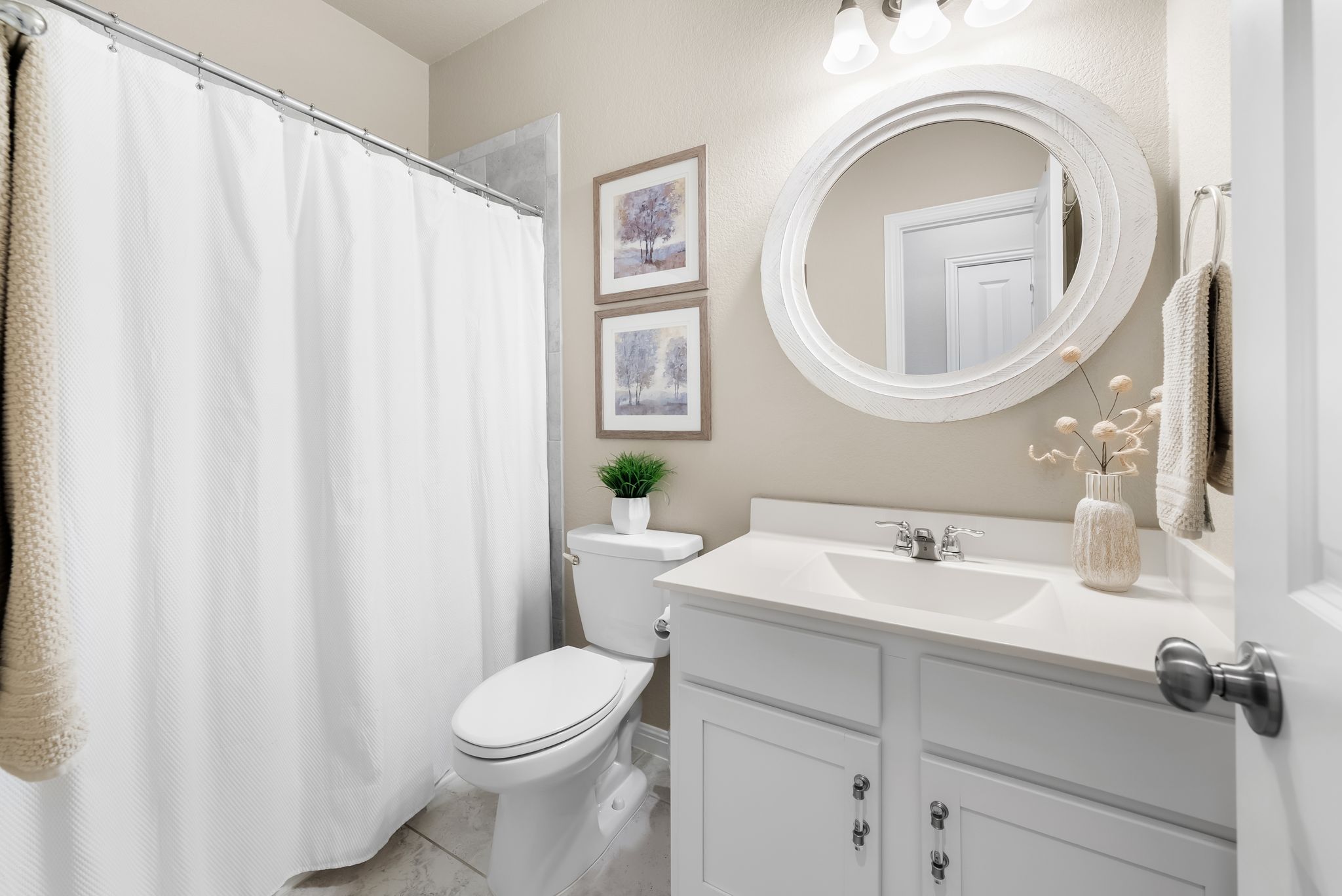300 Prato Place Georgetown, TX 78628 - Photo 27 of 40 A well-lit bathroom features a white vanity, a round mirror, and a convenient shower.