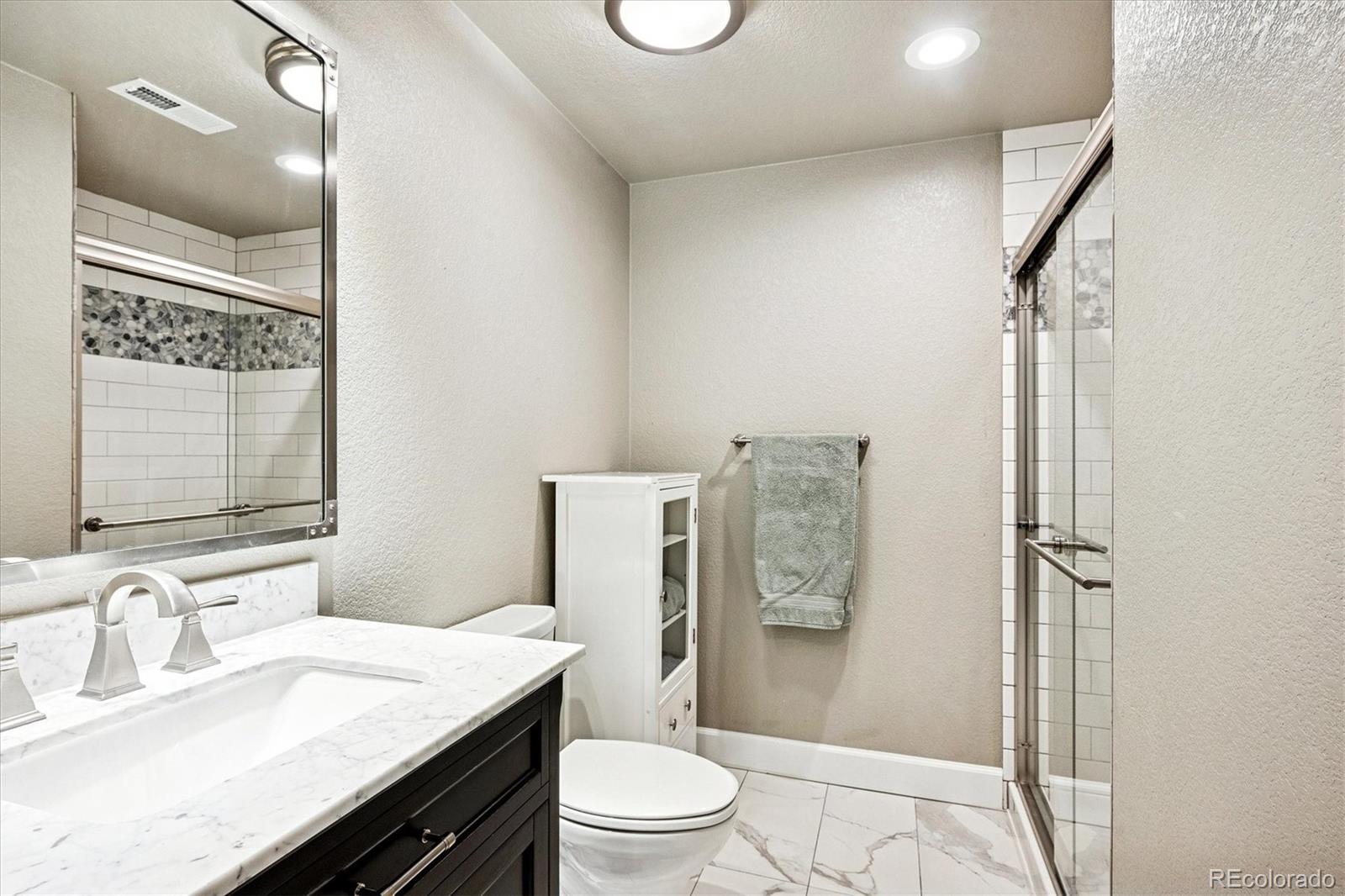 4488 Grapevine Way Castle Rock, CO 80109 - Photo 30 of 46 a bathroom with a granite countertop sink toilet a mirror and shower