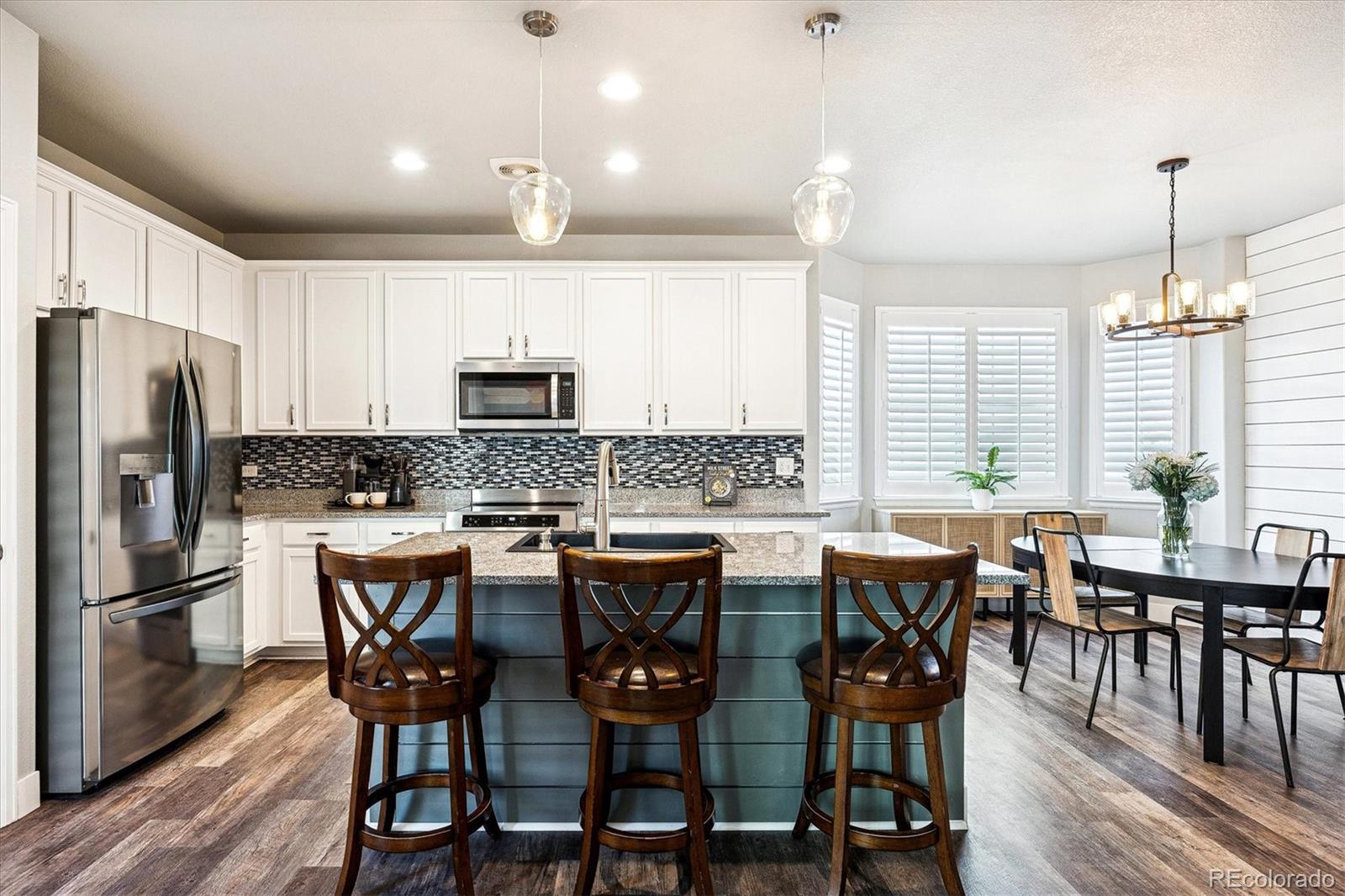 4488 Grapevine Way Castle Rock, CO 80109 - Photo 7 of 46 a kitchen with granite countertop a dining table chairs and refrigerator