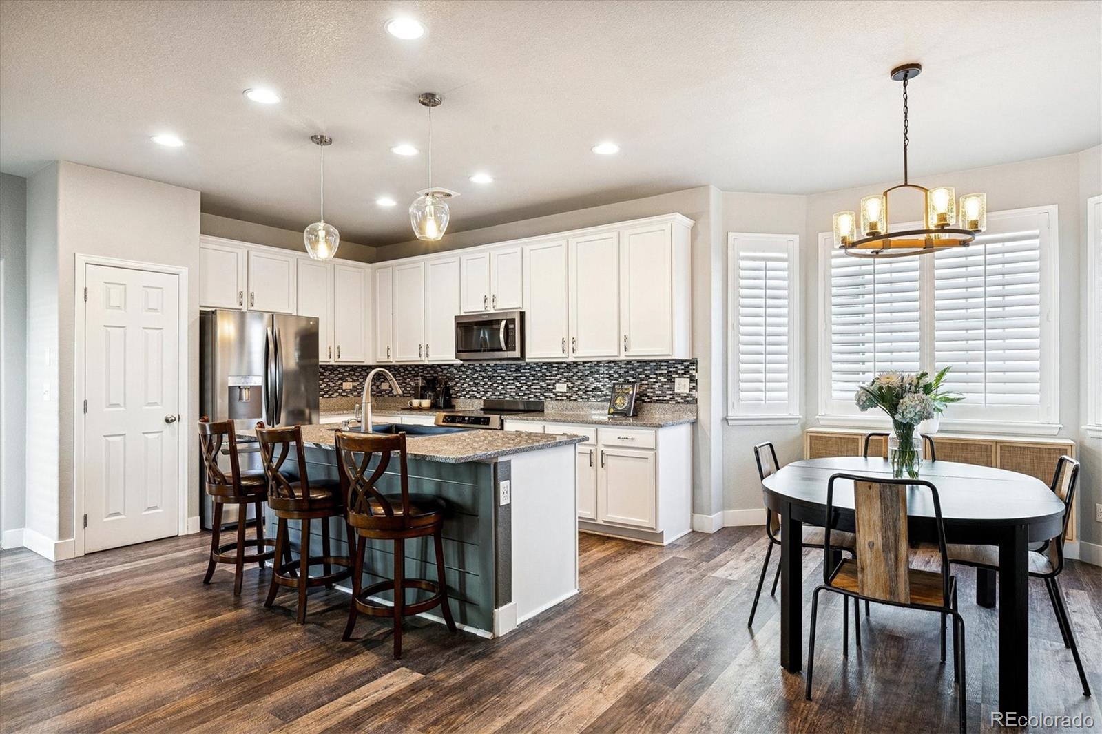4488 Grapevine Way Castle Rock, CO 80109 - Photo 9 of 46 a kitchen with kitchen island a dining table chairs stainless steel appliances and cabinets
