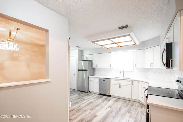 a view of an empty room with wooden floor fireplace and a window