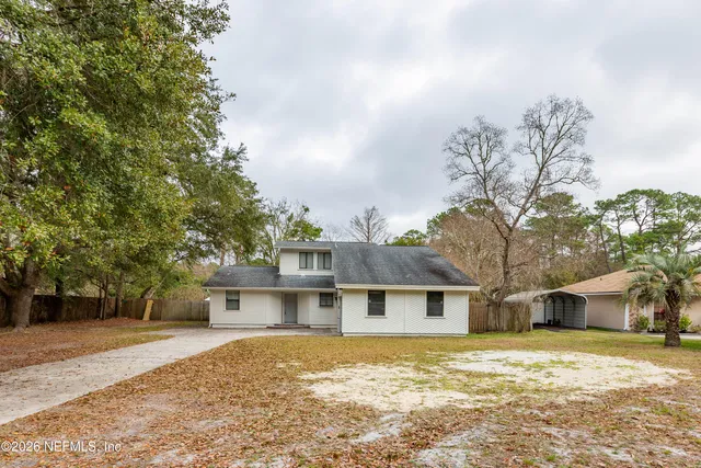 a front view of a house with a yard covered with trees