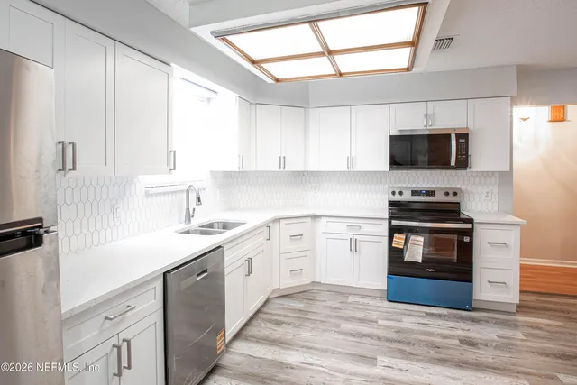 a kitchen with white cabinets and white appliances