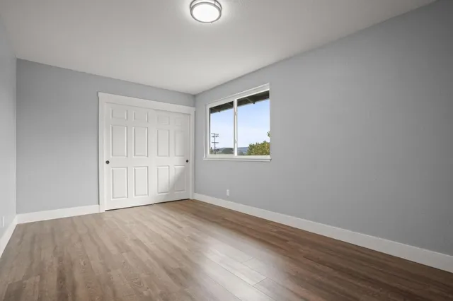 a view of an empty room with wooden floor and a window