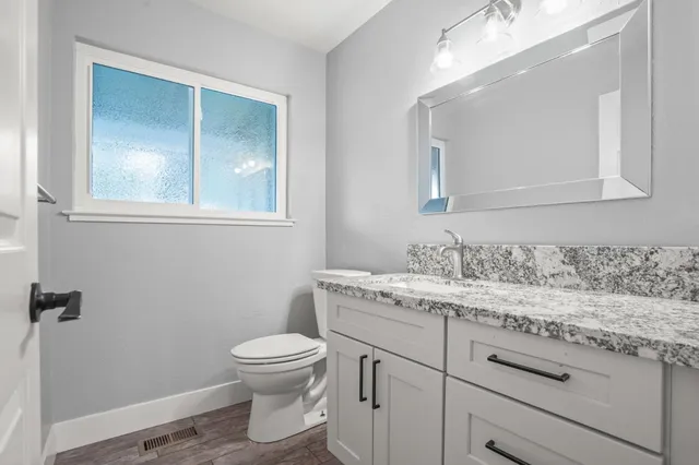 a bathroom with a granite countertop toilet sink and mirror