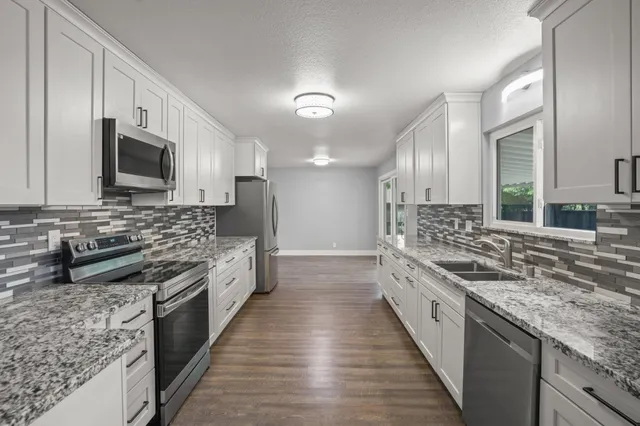 a large kitchen with stainless steel appliances granite countertop a stove sink and cabinets