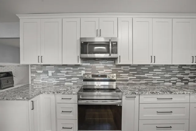 a kitchen with granite countertop white cabinets and stainless steel appliances