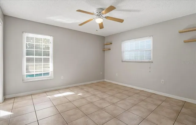 an empty room with windows and fan