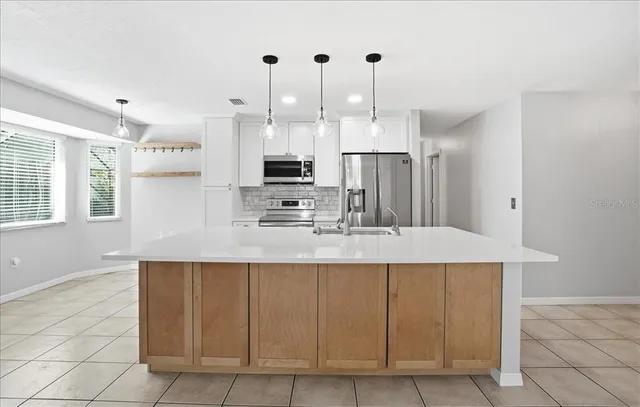 a kitchen with kitchen island granite countertop a sink a counter space appliances and cabinets