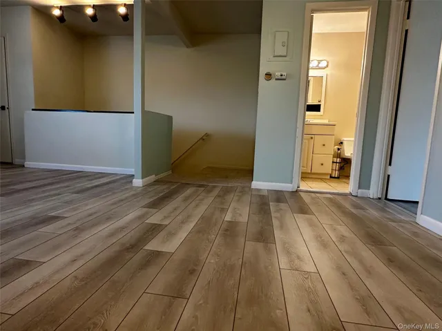 a view of an empty room with wooden floor and a bathroom