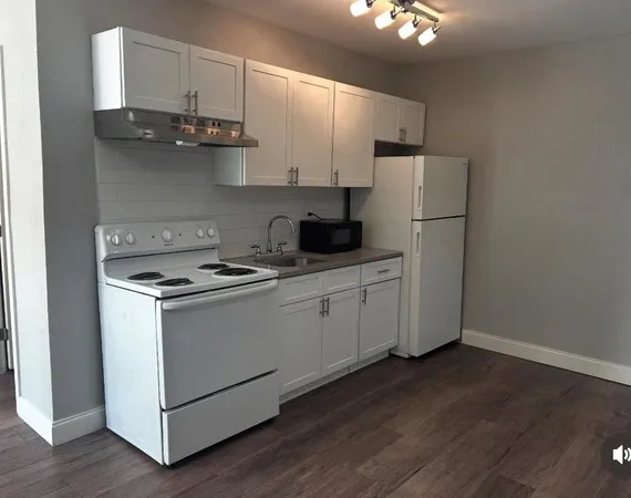 a kitchen with stainless steel appliances granite countertop a refrigerator a stove a sink and white cabinets