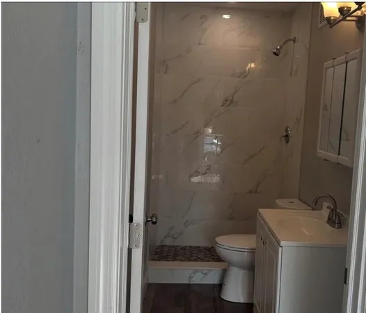 a bathroom with a granite countertop toilet a sink and a shower