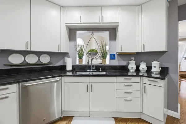a kitchen with granite countertop white cabinets and a wooden floor